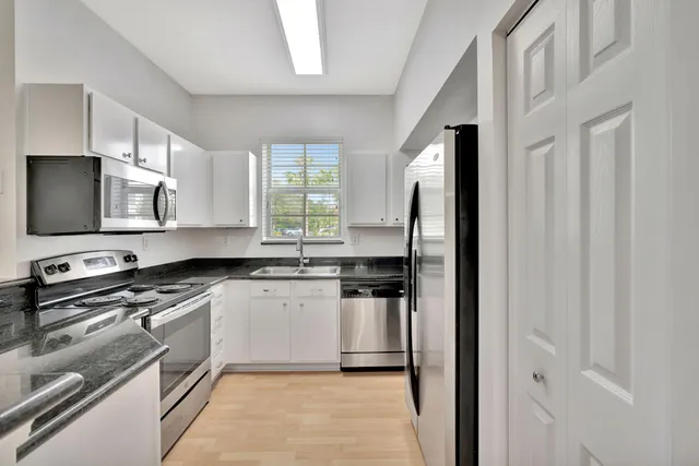 a kitchen with stainless steel appliances granite countertop a stove a sink and a refrigerator