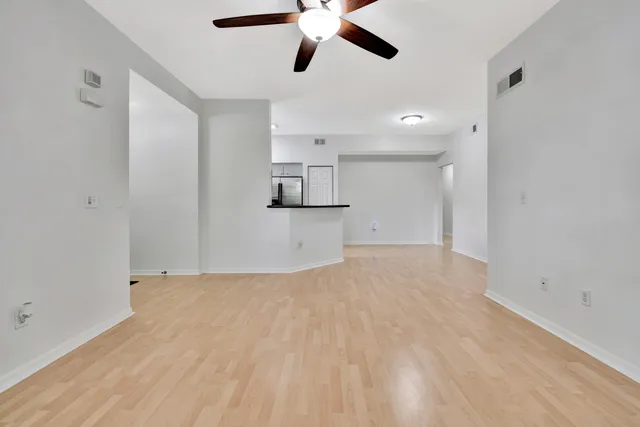 a view of empty room with wooden floor and ceiling fan