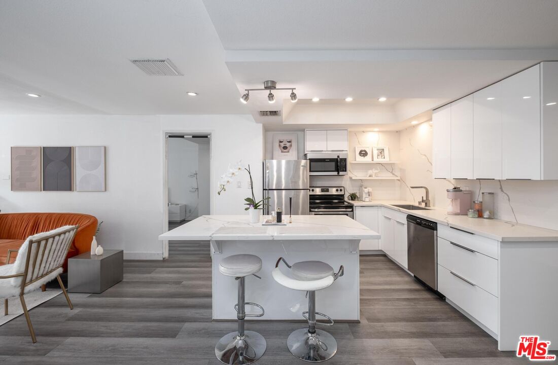 a kitchen with stainless steel appliances kitchen island granite countertop a sink and cabinets