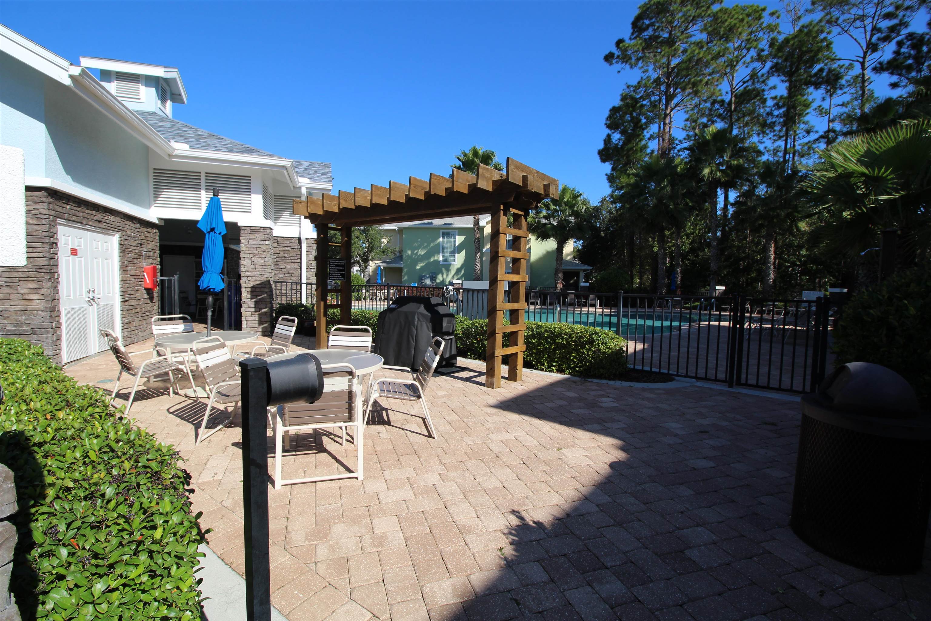 110 Magnolia Crossing Point, Unit 1905 St. Augustine, FL 32086 - Photo 39 of 42 a view of a patio with a table and chairs under an umbrella with wooden fence