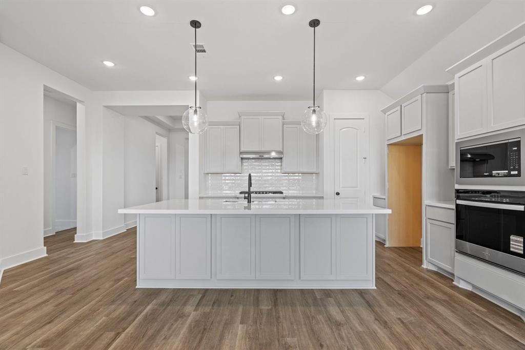 1792 Monarch Way Oak Point, TX 75068 - Photo 9 of 26 a large kitchen with kitchen island white cabinets and stainless steel appliances