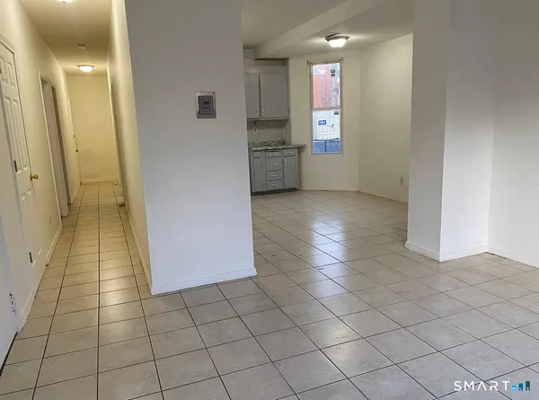 a view of a hallway to an empty room and window