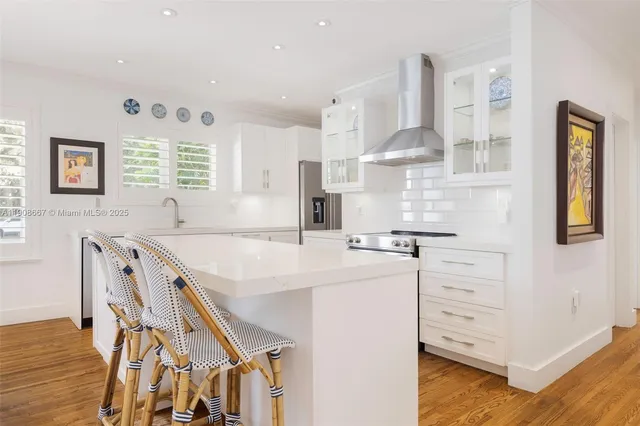 a kitchen with stainless steel appliances white cabinets and wooden floor
