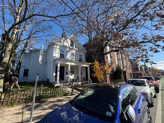 a front view of a building with lots of trees and plants