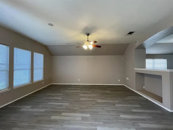 a view of an empty room with a window and wooden floor