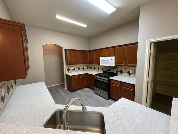 a kitchen with stainless steel appliances kitchen island granite countertop a sink refrigerator and cabinets