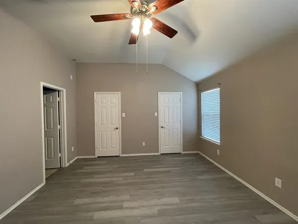 an empty room with wooden floor closet and windows
