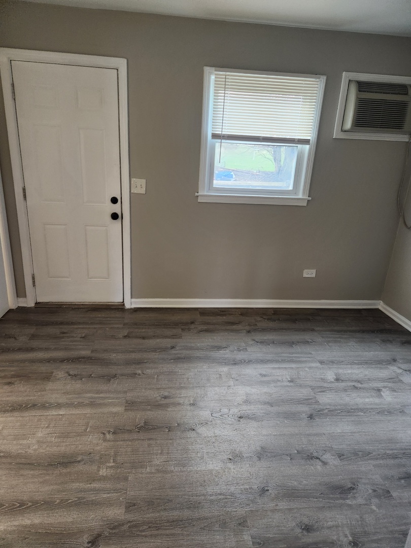 1340 North Main Street, Unit A8 Wheaton, IL 60187 - Photo 2 of 7 a view of an empty room with wooden floor and a window