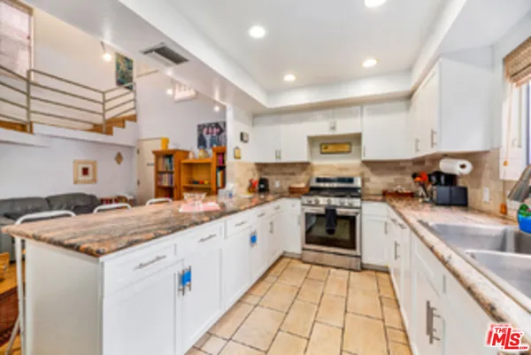 a kitchen with stainless steel appliances kitchen island granite countertop a refrigerator and cabinets