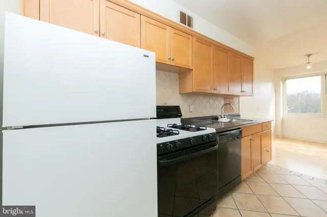 a kitchen with stainless steel appliances a refrigerator a sink a stove and white cabinets
