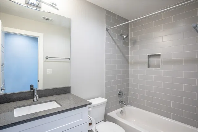a bathroom with a granite countertop bathtub shower sink and toilet