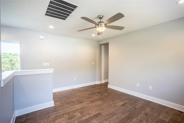 an empty room with wooden floor fan and windows