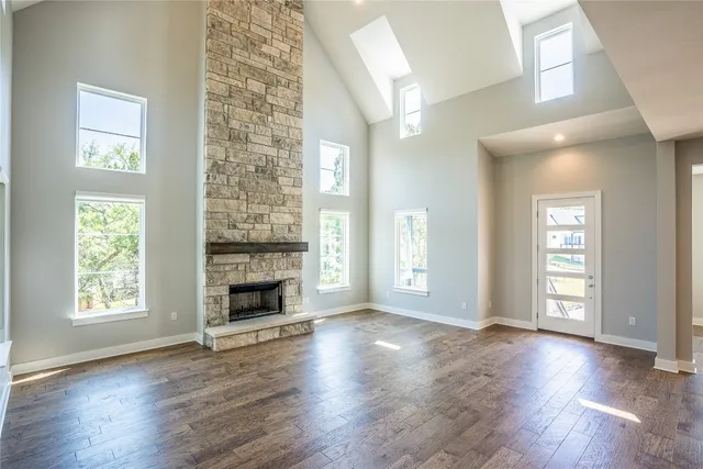 an empty room with wooden floor fireplace and windows