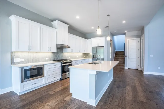 a kitchen with kitchen island white cabinets and stainless steel appliances