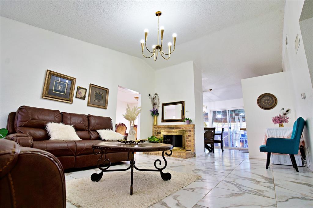 2025 High Bluff Drive Garland, TX 75041 - Photo 6 of 35 a living room with furniture a fireplace and a chandelier