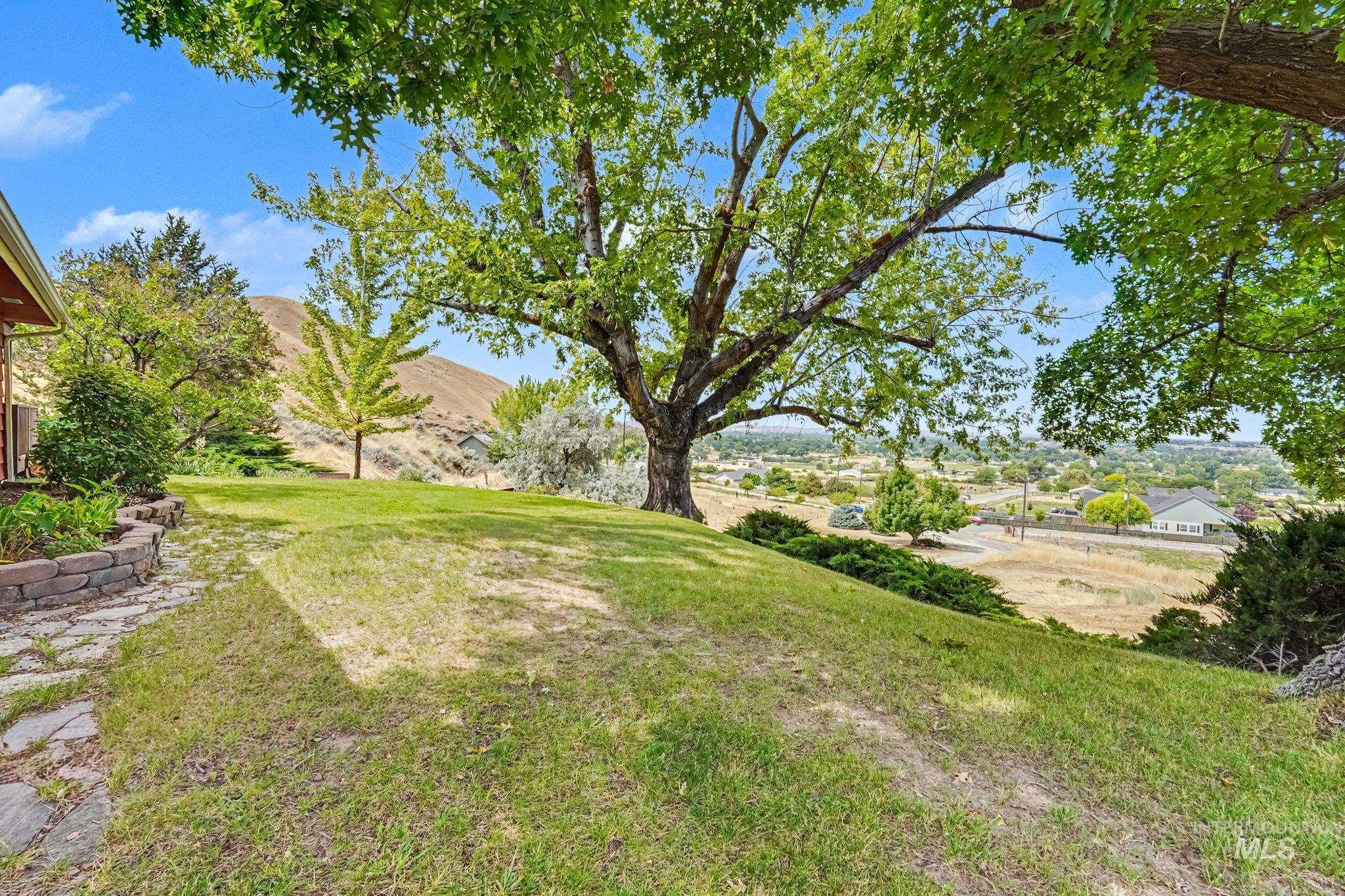 4311 Frozen Dog Road Emmett, ID 83617 - Photo 9 of 31 Expansive sloped lawn with mature trees and a stone-edged garden bed