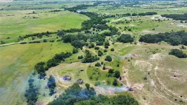 an aerial view of residential houses with outdoor space and trees