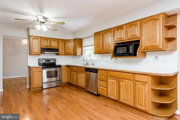 a kitchen with stainless steel appliances granite countertop a sink cabinets and wooden floor