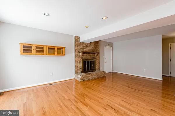 a view of an empty room with wooden floor and a fireplace