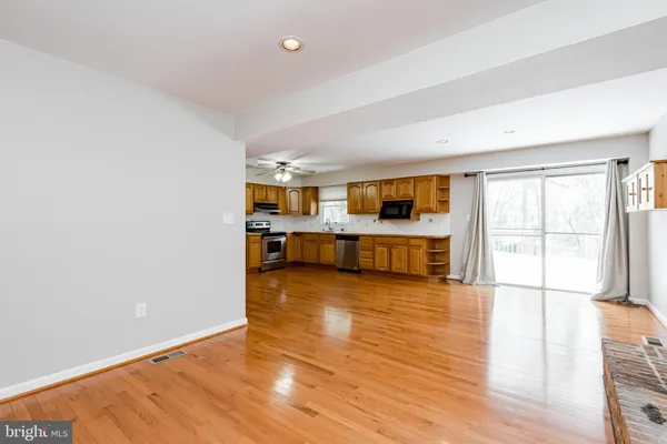a living room with stainless steel appliances kitchen island wooden floors and kitchen view