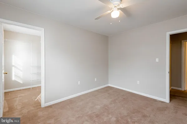an empty room with closet and a chandelier fan