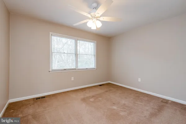 an empty room with windows and ceiling fan