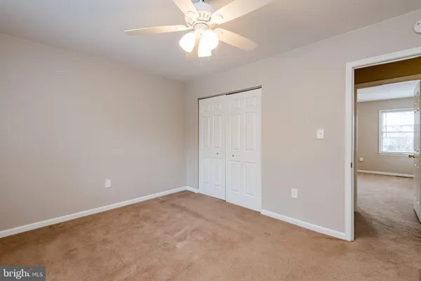 an empty room with a chandelier fan and windows