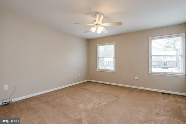 an empty room with windows and fan