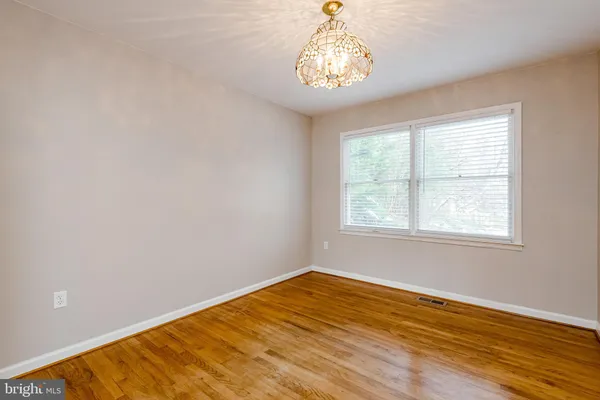 a view of empty room with wooden floor and chandelier