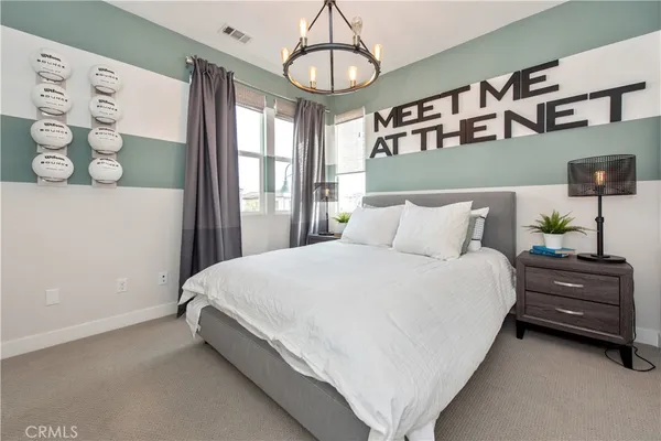 a bedroom with a bed window and a chandelier