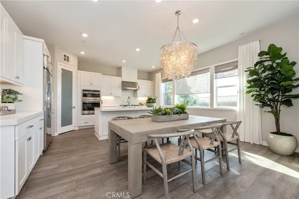 a kitchen with stainless steel appliances kitchen island a table and chairs in it
