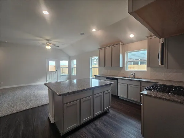 a kitchen with kitchen island granite countertop a sink stainless steel appliances and cabinets