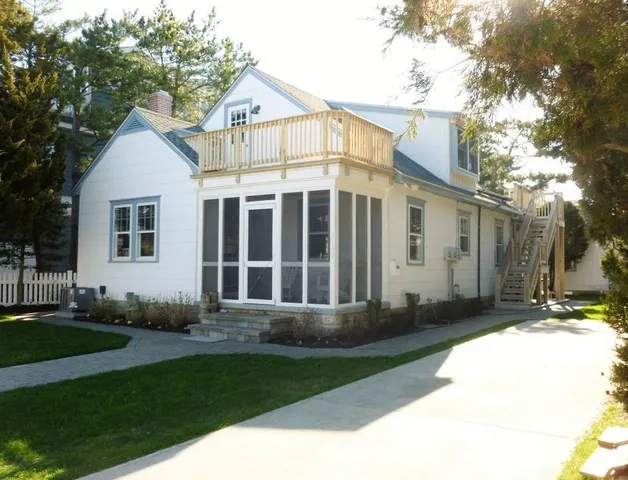 a view of a white house with a big yard and large trees