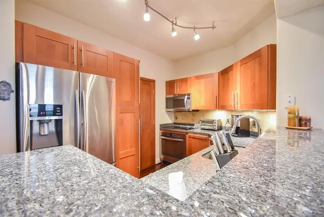 a kitchen with stainless steel appliances granite countertop a refrigerator stove top oven and sink