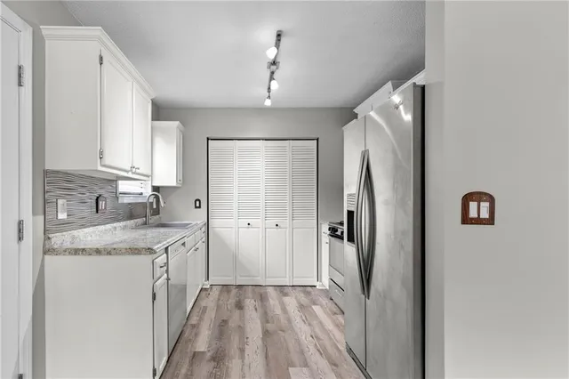 a kitchen with stainless steel appliances granite countertop a refrigerator and a sink