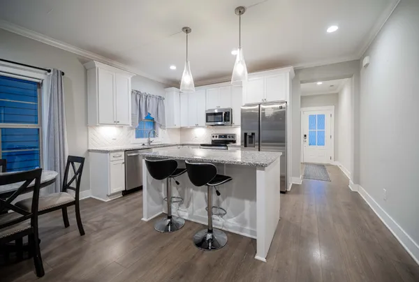 a kitchen with stainless steel appliances kitchen island granite countertop a table chairs refrigerator and microwave