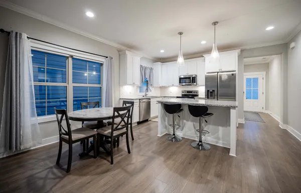 a kitchen with stainless steel appliances a dining table chairs and wooden floor