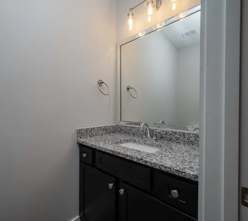 a bathroom with a granite countertop sink and a mirror