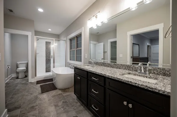 a spacious bathroom with a granite countertop sink a toilet a mirror and a glass door shower