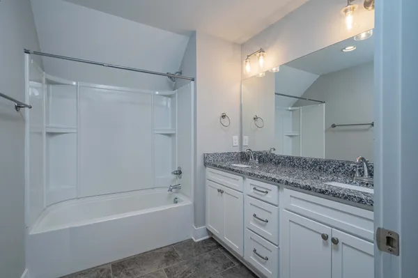 a bathroom with a granite countertop sink a mirror toilet and bathtub