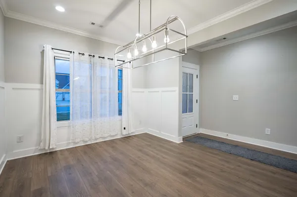 a view of an empty room with wooden floor and fan