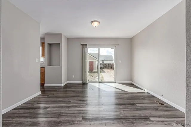 a view of an empty room with glass door and wooden floor