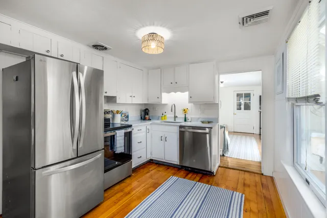 a kitchen with a refrigerator a sink and dishwasher with wooden floor
