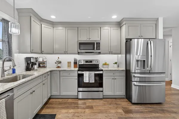 a kitchen with granite countertop stainless steel appliances a dining table and chairs