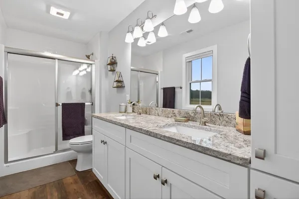 a bathroom with a granite countertop sink a toilet and mirror