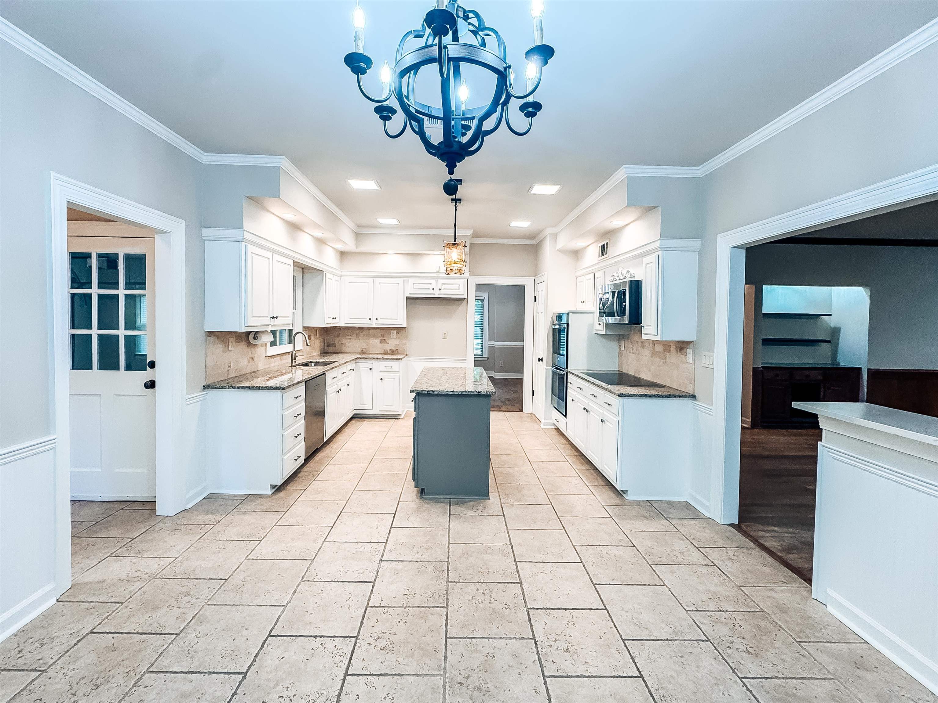 832 South Tree Drive Collierville, TN 38017 - Photo 13 of 40 Spacious kitchen featuring an expansive tile floor, white cabinetry, granite countertops, and a central island with a contrasting base