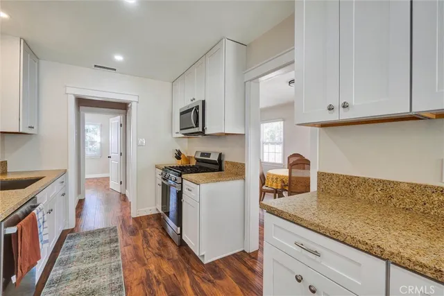 a kitchen with granite countertop a sink a stove top oven a counter space and cabinets