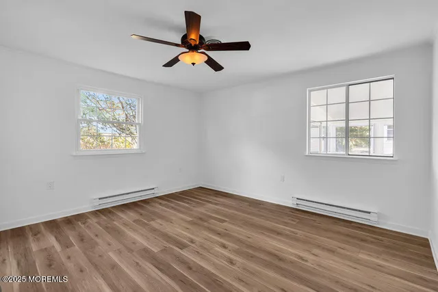 a view of empty room with wooden floor and window