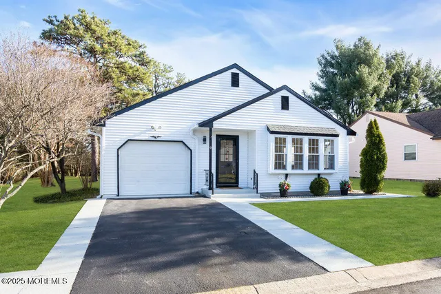 a front view of a house with a yard and trees