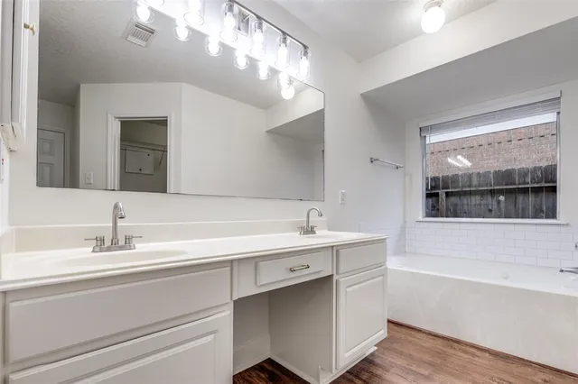 an empty room with wooden floor chandelier and windows